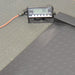 Close-up product view of a Global Industrial 318506 drum scale showing the digital LCD indicator console displaying zero weight, connected power cable, and textured diamond plate steel platform