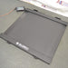 Elevated three-quarter product view of a Global Industrial 318506 drum scale, showcasing the connected digital LCD indicator console, diamond plate steel platform, and integrated ramp profile