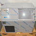 Straight-on front view of a new-in-box Hoshizaki F300BAF flaker ice maker on a wooden shipping pallet, showing protective film wrapping on the stainless steel body, lower black louvered grill, and front access door