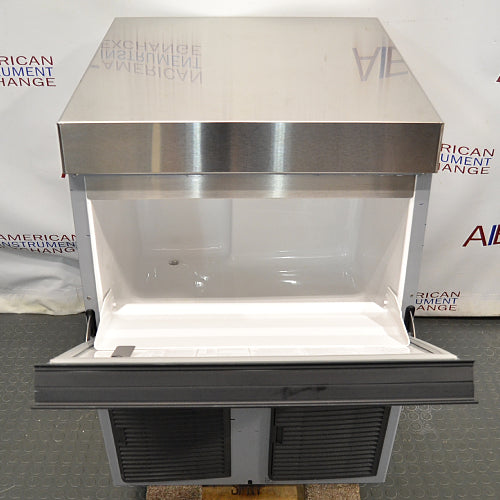 Front product view of a Hoshizaki F330 BAJ flaker ice maker with its front bin door opened downward, exposing the empty white interior storage bin and stainless steel top housing