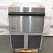 Front product view of a Hoshizaki F330 BAJ flaker ice maker, showcasing its stainless steel bin door with a black handle, polished top housing, and lower louvered panels