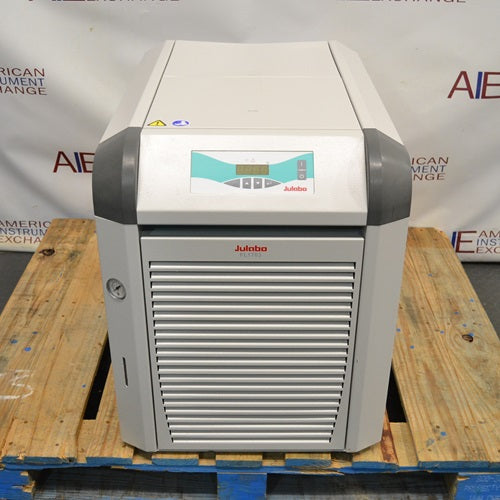 Julabo FL1703 recirculating chiller sitting on a wooden pallet showing front louvered ventilation grille, pressure gauge on left panel, and top digital control display