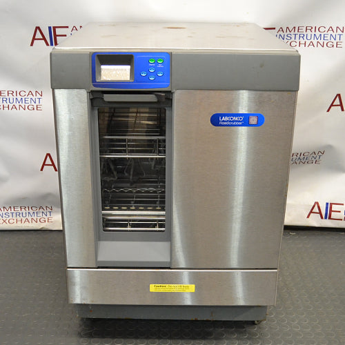 Front eye-level view of a Labconco Freestanding Glassware Washer (Model 4420430) on a dark textured surface, featuring its stainless steel and gray housing, blue control panel insert, Labconco FlaskScrubber branding badge, and a lower-tier drop-down glass door revealing internal wire racks