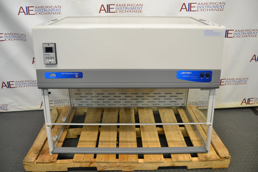 Front eye-level view of a Labconco XPert Filtered Balance System mounted on a wooden pallet, featuring its top filter housing, digital monitor unit, control switches, and clear enclosure frame
