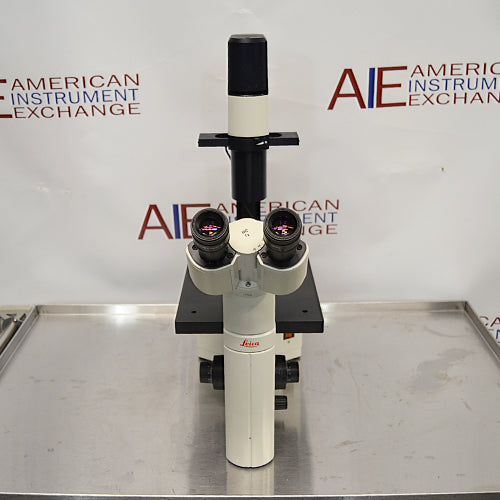 Leica DM IRB inverted research microscope ka front view, jisme dual eyepieces wala binocular head, stage platform, vertical camera/illumination tube, aur Leica branding saaf dikhai de rahe hain.