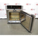 Front view of an open Memmert Universal Oven UN30 showing the internal stainless steel heating chamber with a wire shelf grid and open door