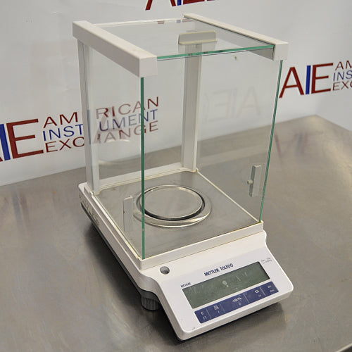 Mettler Toledo ME104E analytical balance ka right angle view, jisme right glass draft shield panel, circular weighing pan, digital screen, aur front control keypad saaf dikhai de rahe hain.   