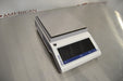 Angled perspective view of a Mettler Toledo MS3002TS precision balance resting on a stainless steel surface showcasing its profile, weighing pan, and digital control panel