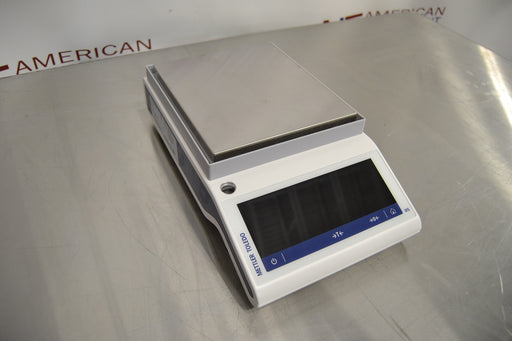 Angled perspective view of a Mettler Toledo MS3002TS precision balance resting on a stainless steel surface showcasing its profile, weighing pan, and digital control panel