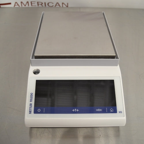 Front eye-level view of a Mettler Toledo MS3002TS precision balance resting on a stainless steel surface featuring a square weighing pan and a digital touchscreen display panel