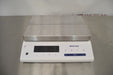 Front eye-level view of a Mettler Toledo MS32001L precision balance resting on a stainless steel surface, showcasing its large stainless steel weighing pan and digital display control panel