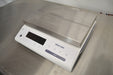 Left elevated angled view of a Mettler Toledo MS32001L precision balance resting on a stainless steel counter, featuring its flat stainless steel weighing platform and front digital display interface