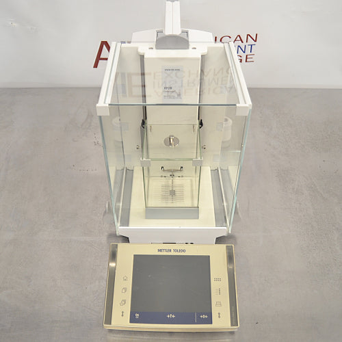 Mettler Toledo XP26DR microbalance ka top angle view, jisme glass draft shield ka upar ka hissa, internal weighing chamber, aur touch screen display terminal saaf dikhai de rahe hain.   