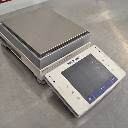 Mettler Toledo XPE1202S precision balance ka left angle view, jisme left side weighing unit housing, detachable touch screen terminal, aur stainless steel pan saaf dikhai de rahe hain.   