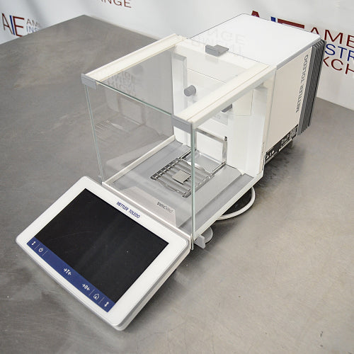 Mettler Toledo XPR106H dual-range analytical balance ka left angle view, jisme glass draft shield ka left side, precision weighing pan, aur front par laga hua touch screen terminal saaf dikhai de raha hai.   