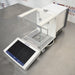Mettler Toledo XPR106H dual-range analytical balance ka left angle view, jisme glass draft shield ka left side, precision weighing pan, aur front par laga hua touch screen terminal saaf dikhai de raha hai.   