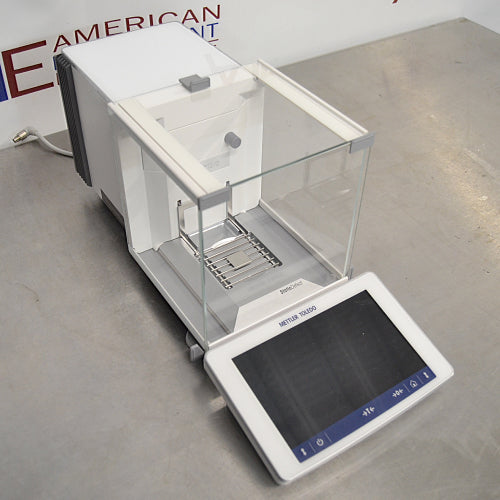Mettler Toledo XPR106H dual-range analytical balance ka right angle view, jisme glass draft shield ka right side, precision weighing pan, aur front par laga hua touch screen terminal saaf dikhai de raha hai.   