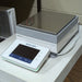 Left three-quarter angle product view of a Mettler Toledo XSR10002S precision balance, featuring the stainless steel weighing pan, digital touch terminal display, and housing on a laboratory bench