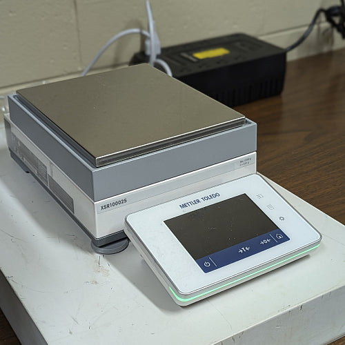 Three-quarter angle product view of a Mettler Toledo XSR10002S precision balance, featuring the stainless steel weighing platform, digital touchscreen terminal, and housing on a lab bench