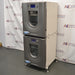 Right three-quarter angle product view of a New Brunswick Innova 42R stacked refrigerated incubator shaker system, showcasing the dual stacked grey chassis units, side panels, curved doors with central viewing windows, digital displays, and adjustable leveling feet