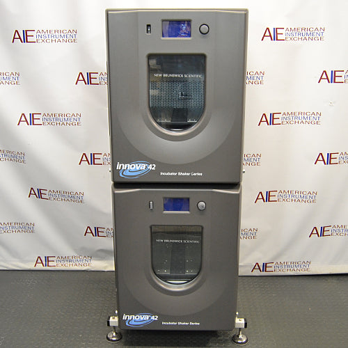 Front product view of a New Brunswick Innova 42R stacked refrigerated incubator shaker system, featuring two vertically mounted grey units with curved doors, central glass windows, digital control displays, and leveling feet