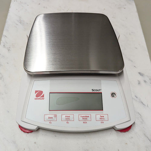 Top-down product view of an Ohaus Scout SPX2201 portable balance, featuring a rectangular stainless steel weighing pan and a front-facing digital display with control buttons