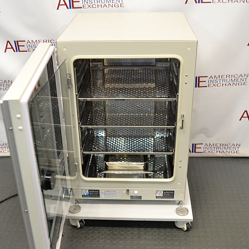 Studio angle product view of a Panasonic Cell-IQ Series MCO-170AICUVL-PA CO2 cell culture incubator with the outer door swung open against a branded backdrop, highlighting its off-white housing, open internal chamber with perforated stainless steel shelves, a lower water reservoir pan, and wheeled platform base