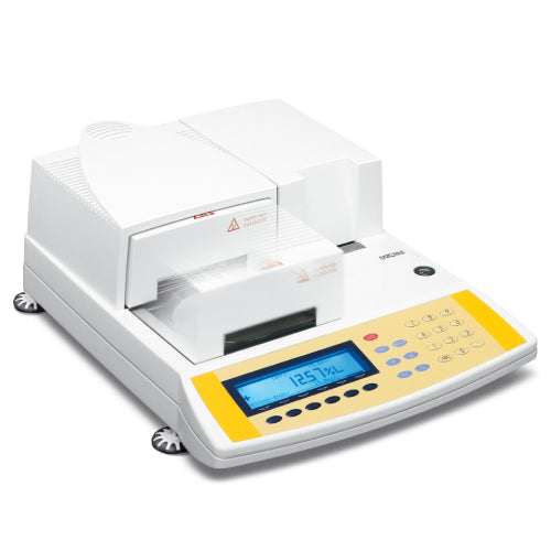 Left angle product view of a Sartorius MA100 infrared moisture analyzer with halogen heater, featuring its white and yellow housing, front sliding sample chamber door, blue LCD screen, and integrated keypad