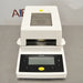 Front high angle product view of a Sartorius MA35 infrared moisture analyzer, showcasing its white housing, top mesh ventilation panel, sample chamber opening, and angled front control interface