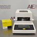 Front product view of a Sartorius MA35 infrared moisture analyzer accompanied by a box of Sartorius sample pans, featuring the white and black housing, digital control panel, and heating chamber
