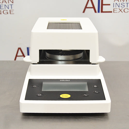 Front product view of a Sartorius MA35 infrared moisture analyzer, featuring a white and black housing, central sample chamber opening, and a front control panel with a digital display and yellow enter button