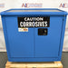 Front view of an unused Securall 24-gallon corrosive storage cabinet in bright blue, featuring a prominent CAUTION CORROSIVES warning label, locking handle, and dual doors resting on a wooden pallet base