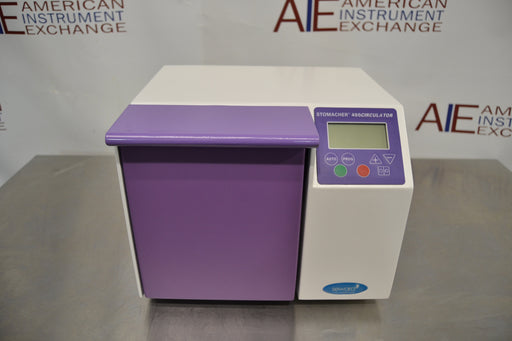 Front eye-level view of a Seward Stomacher 400 Circulator lab blender, featuring a white cabinet body with a purple paddle chamber door, top digital control panel, and LCD screen resting on a stainless steel counter