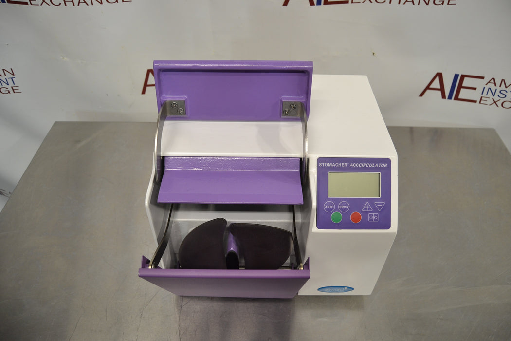 Top-down view of a Seward Stomacher 400 Circulator lab blender with its purple paddle door open, revealing the internal curved blending paddles, chamber mechanism, and right-side digital control screen