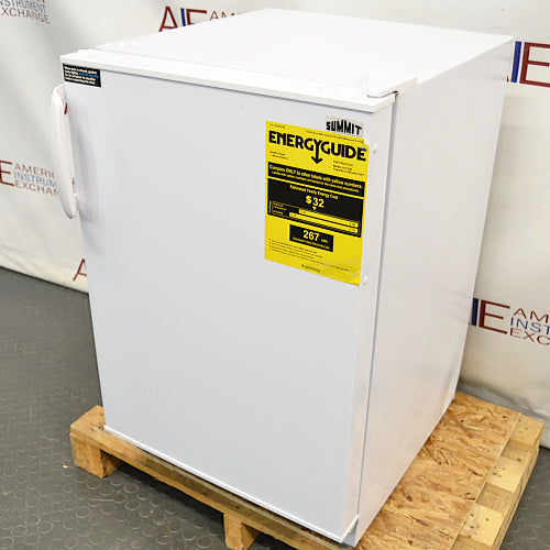 Right angled perspective view of a Summit undercounter all-freezer on a wooden pallet, showcasing its white cabinet body, solid front door with an ergonomic handle, and a yellow EnergyGuide label