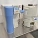 Left angle view of a Thermo GenPure Pro UV/UF water purification system, showcasing the blue front housing panel, digital control interface, dispensing valve, and adjacent storage tank on a steel bench   