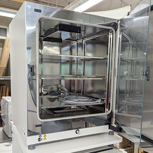 Three-quarter product view of a single Thermo Heracell VIOS 250i CO2 incubator with its outer door open, showcasing the polished stainless steel interior chamber, adjustable wire shelves, and inner glass door