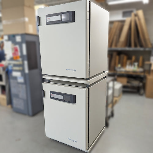 Low angle product view of a stacked dual Thermo Heracell VIOS 250i CO2 incubator system in a warehouse, highlighting the vertical configuration, digital control interfaces, and side panels