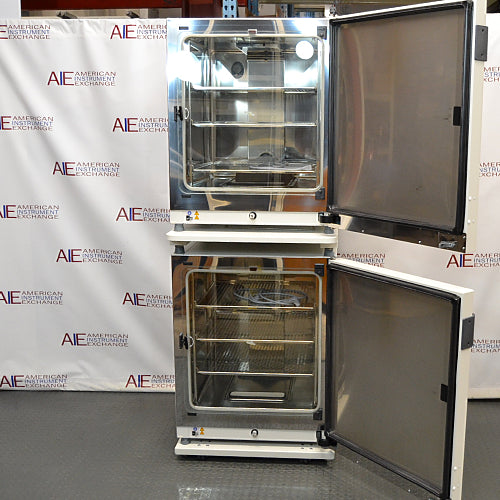 Front product view of a stacked dual Thermo Heracell VIOS 250i CO2 incubator system with both outer doors open, revealing the stainless steel interior chambers, adjustable wire shelves, and glass inner doors