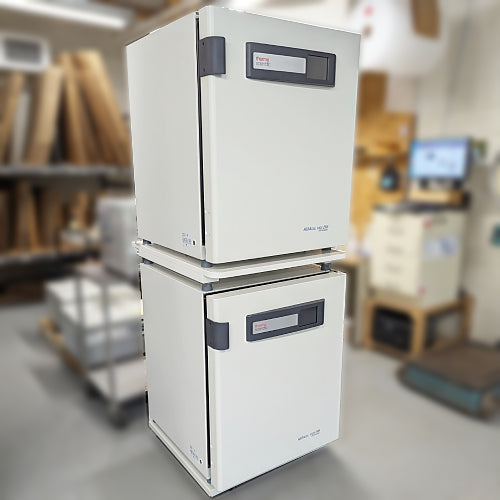 Three-quarter angle product view of a stacked dual Thermo Heracell VIOS 250i CO2 incubator system in a facility, highlighting the vertical arrangement, top control panels, and side-opening doors on both units