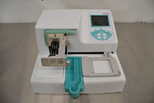Front product view of a Thermo Multidrop Combi reagent dispenser, featuring its white housing, integrated digital display, teal control keypad, dispensing cassette mechanism, and microplate stage