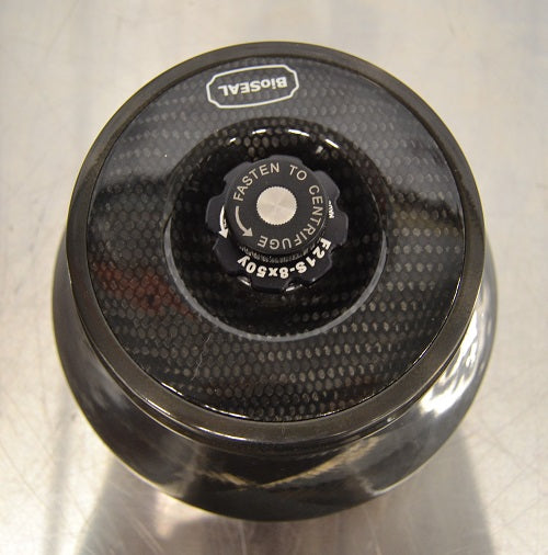 Top-down view of a Thermo Scientific Fiberlite F21S-8x50Y carbon fiber centrifuge rotor resting on a stainless steel surface featuring a BioSeal lid and central locking knob