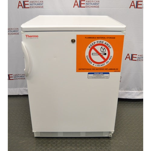 Front view of a white Thermo Scientific undercounter flammable material storage refrigerator featuring a key lock and a prominent orange flammable safety warning label on the door