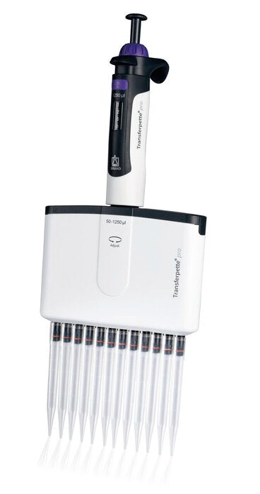 A front view of an upright BRANDTECH Transferpette S 12-channel adjustable pipette featuring a white body with green accents, a digital volume display window, top plunger button, and twelve clear pipette tips attached at the base.