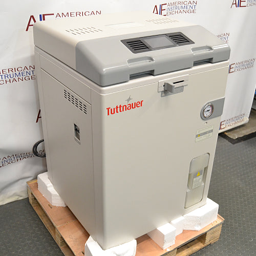 Left angle product view of a Tuttnauer LabSci 85LV vertical autoclave secured on a wooden shipping pallet with foam packaging, highlighting its beige body panels, grey control console, and side ventilation