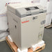 Left angle product view of a Tuttnauer T-Lab Eco V60 60L vertical laboratory autoclave secured on a wooden shipping pallet, highlighting its beige housing, grey top console with digital interface, and lower water reservoir
