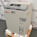 Right angle product view of a Tuttnauer T-Lab Eco V60 60L vertical laboratory autoclave on a wooden shipping pallet, showing its beige enclosure, grey top control console, integrated pressure gauge, and front lower water tank