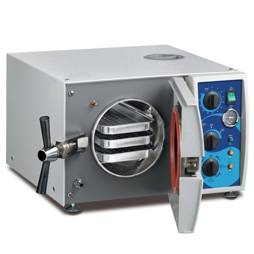 Front angle product view of a Tuttnauer Valueklave 1730 manual tabletop autoclave with its front door open, showing the orange door seal gasket, cylindrical stainless steel internal chamber, and loaded instrument trays