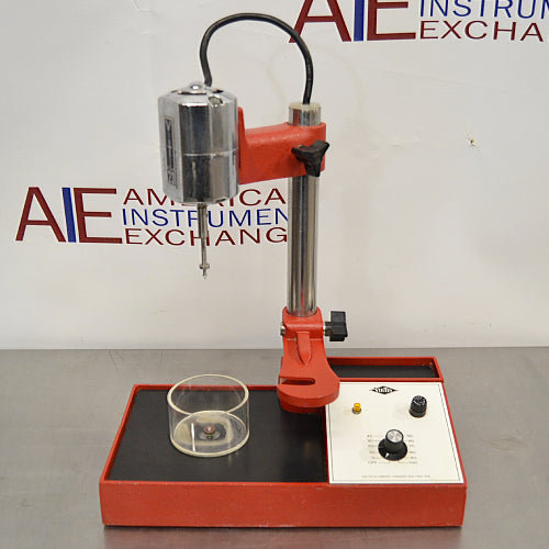Front product view of a Virtis Model 23 micro homogenizer, featuring a red and chrome motor drive mounted on an adjustable vertical support post, base platform with control panel, speed dial, and glass container on a stainless steel lab bench