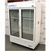 Left angled perspective view of a VWR double door chromatography refrigerator showcasing its white exterior casing, glass doors, vertical handles, internal wire shelves, and lower vented grill panel